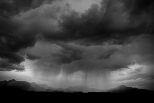 A cloudburst drops virga across the mountain landscape.